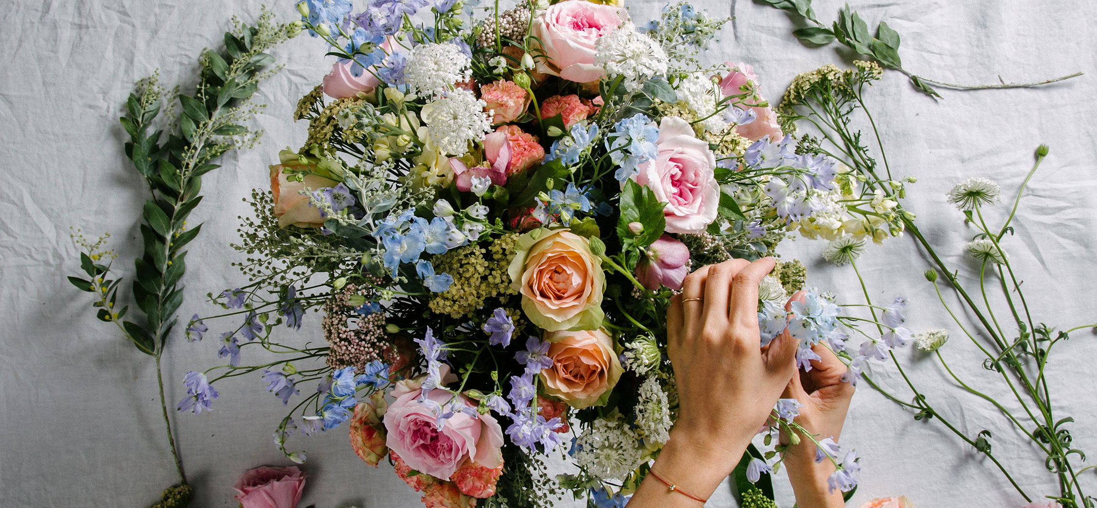 Florist arranging a luxury flower bouquet of garden rose and delphinium. Featuring bespoke bouquet 34.