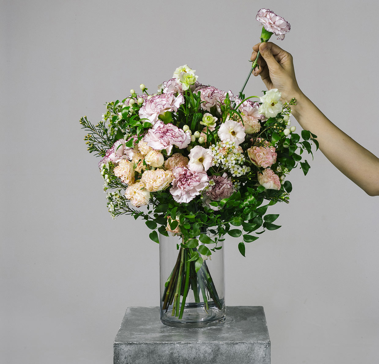 florist arranging a flower bouquet of pink carnation and ranunculus for the bespoke collection