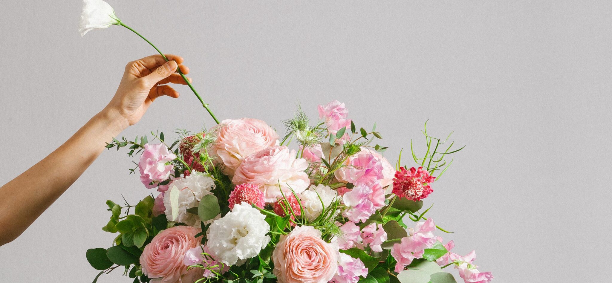 Florist arranging a luxury flower bouquet of ranunculus and rose. Featuring bespoke bouquet 7.
